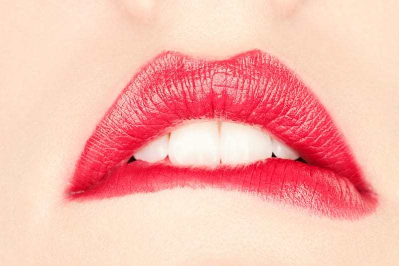 Red lips proudly scrape off creamy lipstick while pronouncing the letter F.