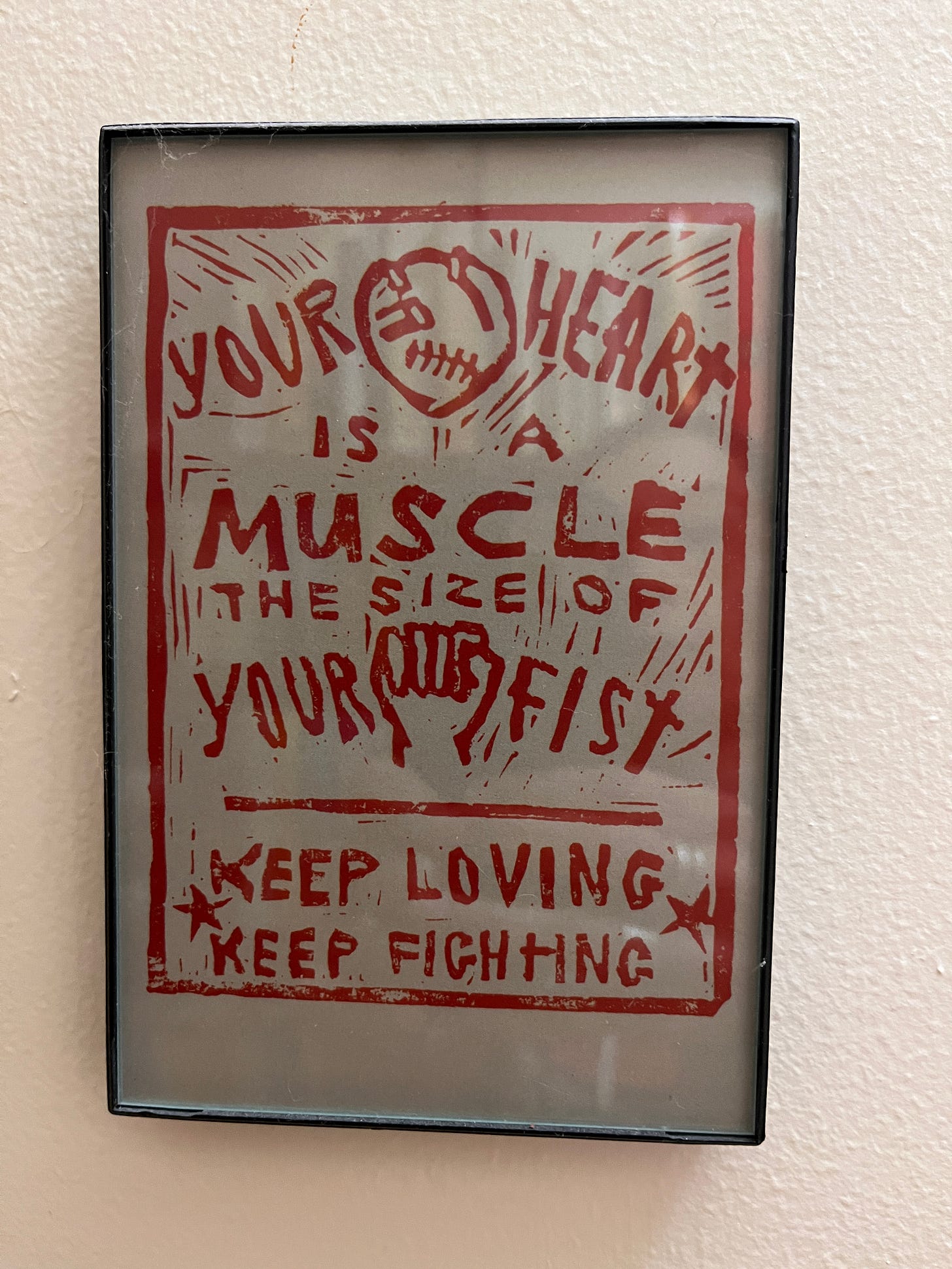 A red woodcut image with a fist and heart and the slogan "your heart is a muscle the size of your fist; keep loving; keep fighting."