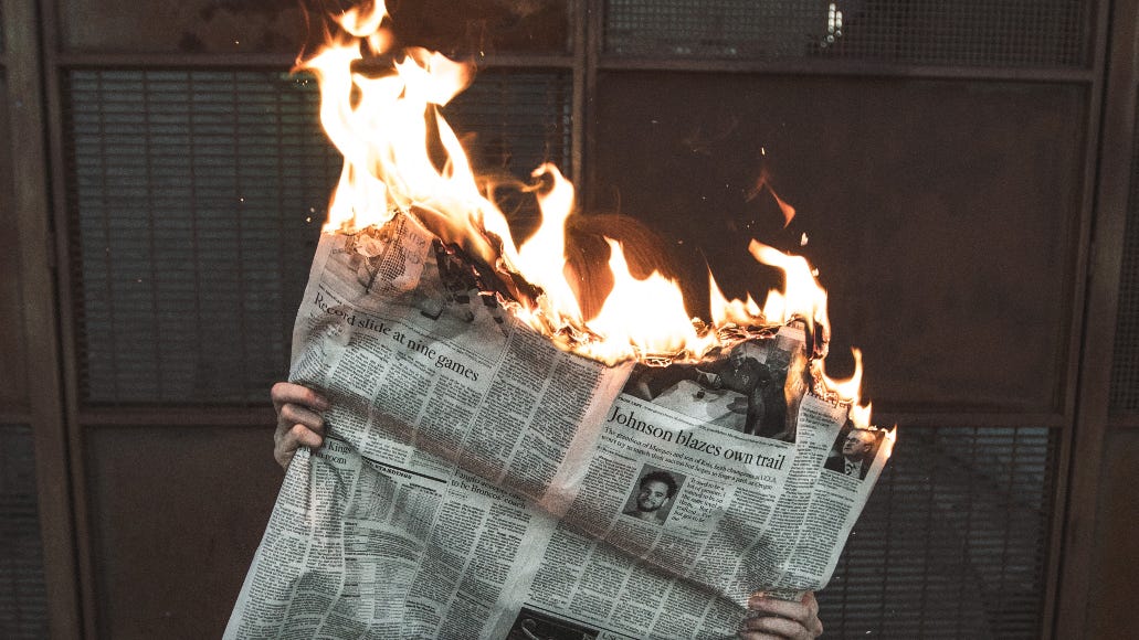 Someone reading a newspaper while the top burns