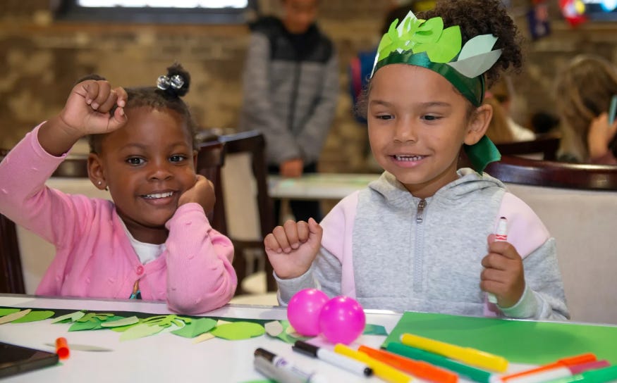 Two children sitting at a table taking part in a craft workshop