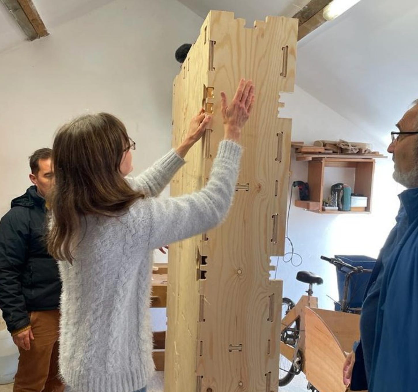3 people can be seen building a WikiHouse block made from plywood