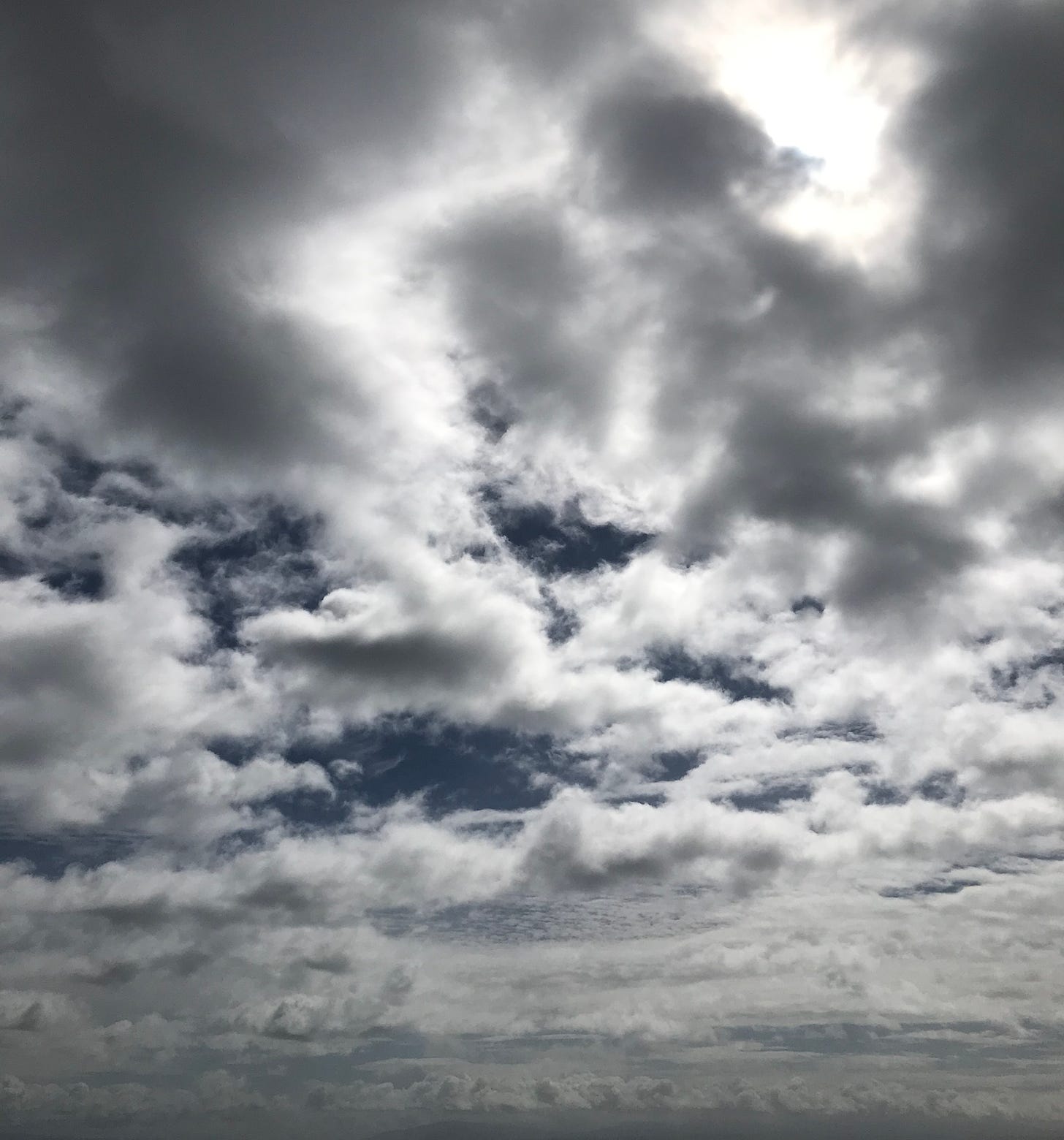 Large rain clouds with openings to sunlight and blue sky