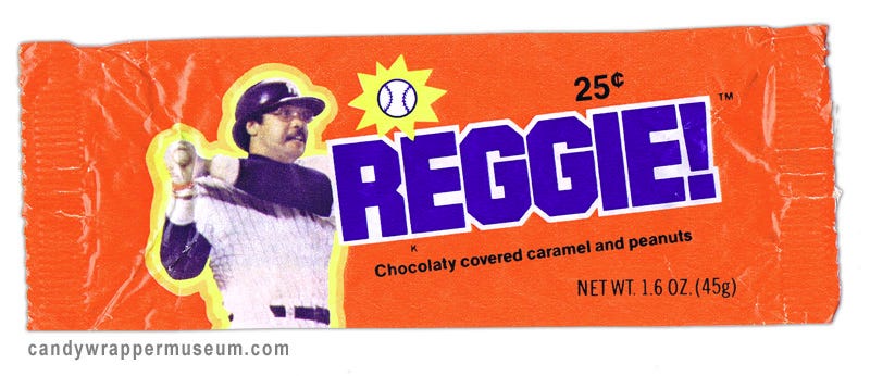 The orange-colored wrapper of a Reggie! bar. Baseball great Reggie Jackson is pictured completing his famous left-handed home-run swing. A baseball, pictured in mid-flight, is surrounded by a yellow star. Text near the bottom of the wrapper reads "Chocolaty covered caramel and peanuts."