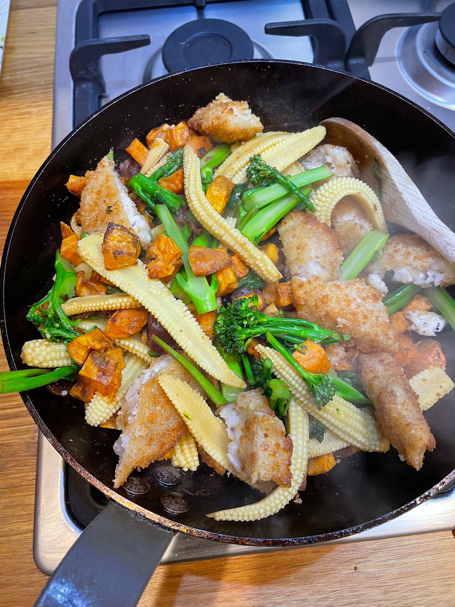 Fry pan with a just-cooked stir fry including chopped fish fingers, baby corn, baked sweet potato, broccolini from Lara Lee's new cookbook.