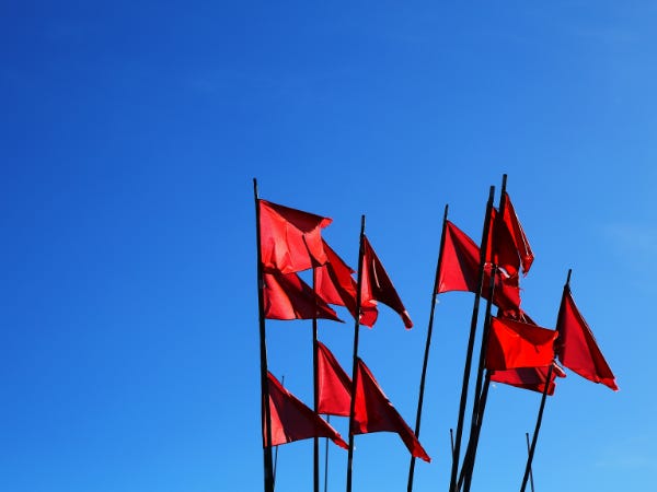 Group of red flags flapping against a cloudless blue sky