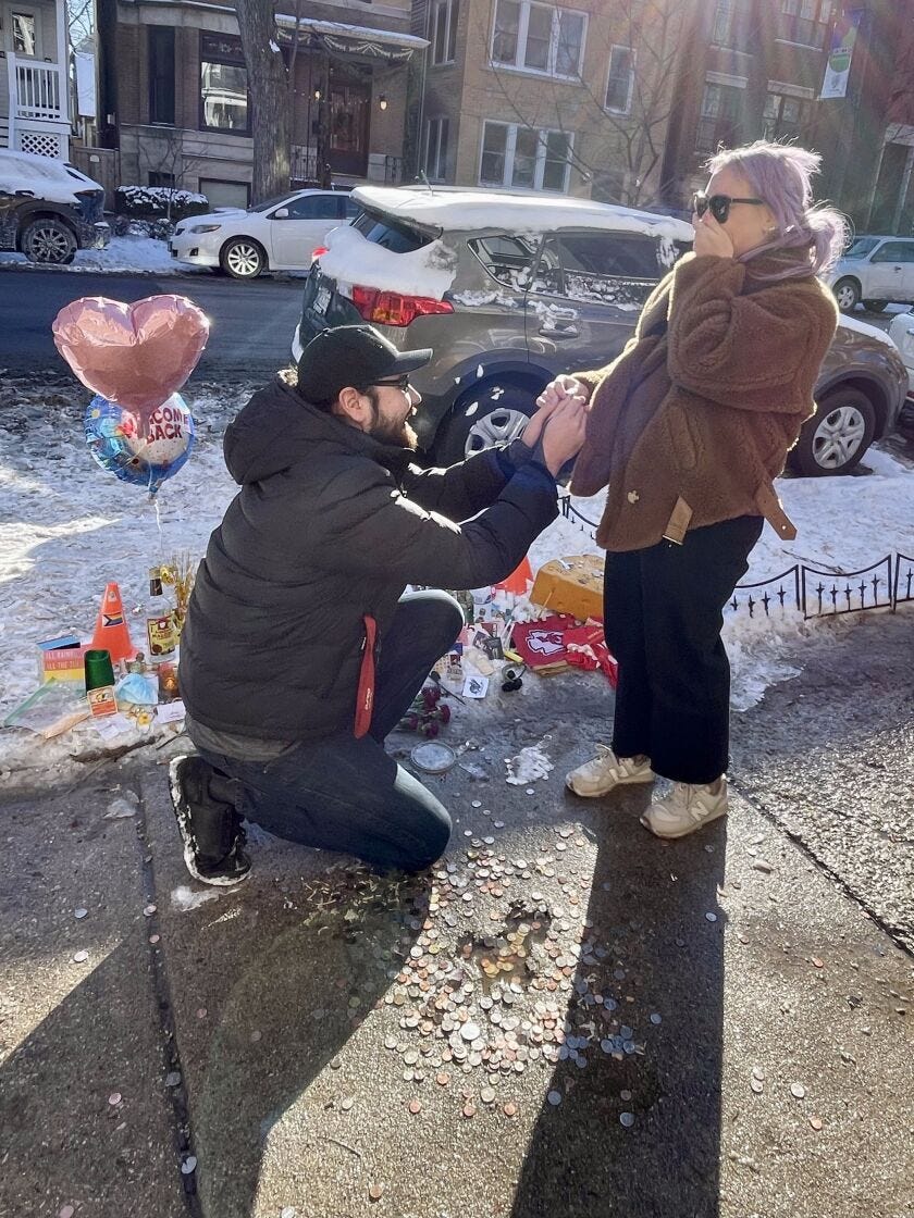 Michael Obler kneels in front of Molly Widstrom as they get engaged amid snow at the Chicago rat hole, as a few mylar balloons float behind them.