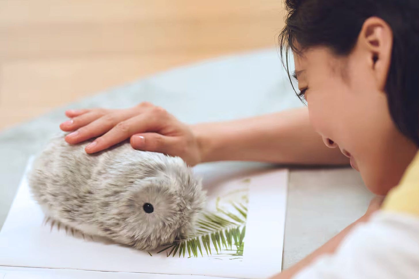 A person pets the top of Casio’s Moflin robotic pet.