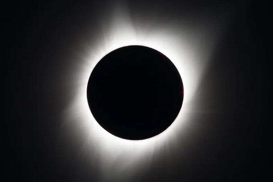 An up-close image of a total solar eclipse, showing the sun completely blocked out by the moon surrounded by a glowing corona.