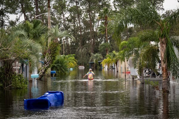 A flooded street with a woman standing in the middle. 