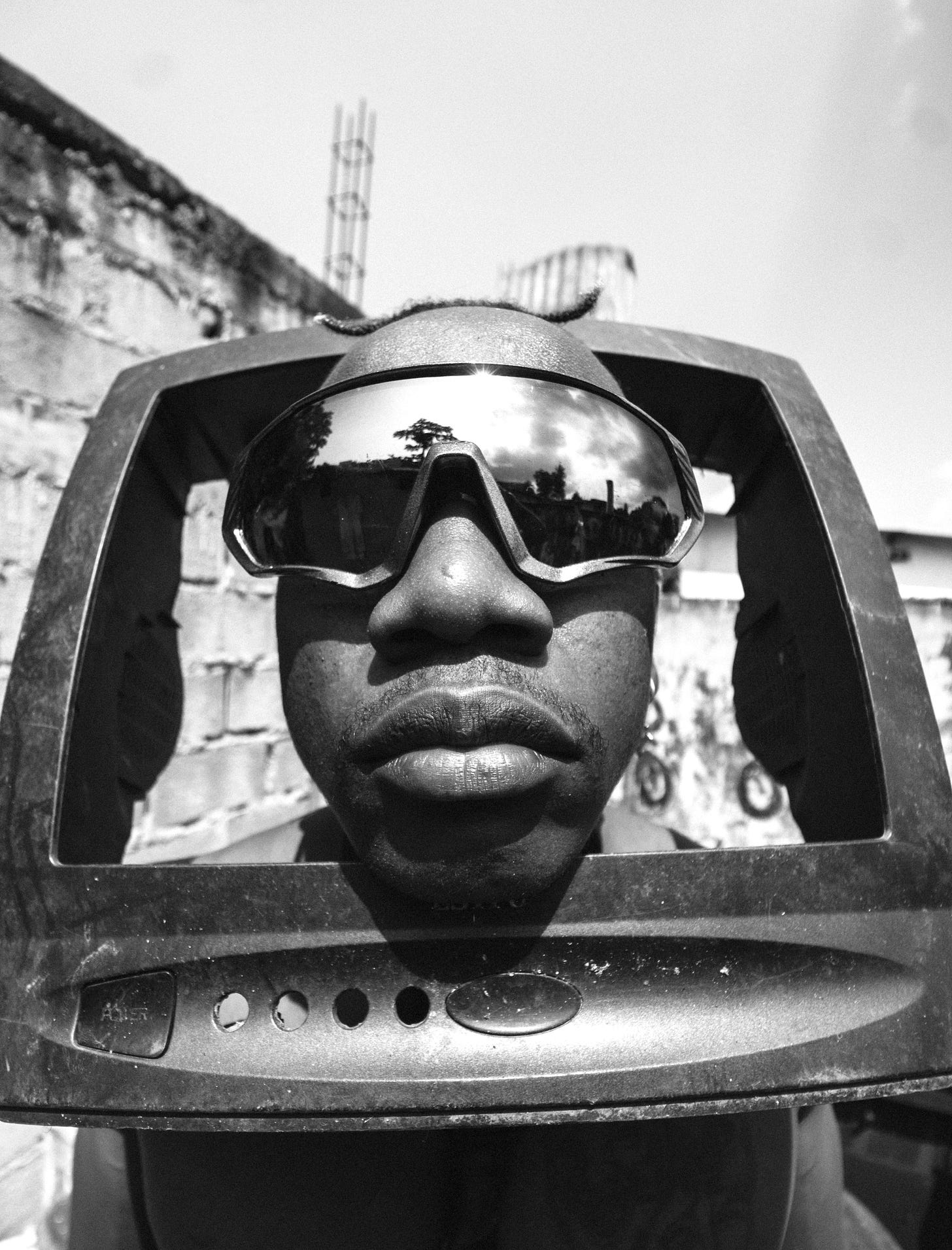 A man wearing glasses, his head is inside an old school television