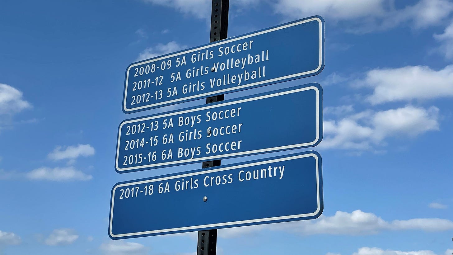 Blue signs listing Coppell High School champions since 2008 in white type