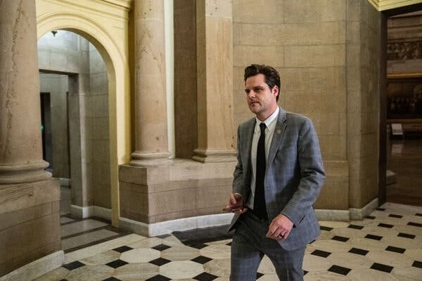 Representative Matt Gaetz walking with a phone in his hand in the Capitol.