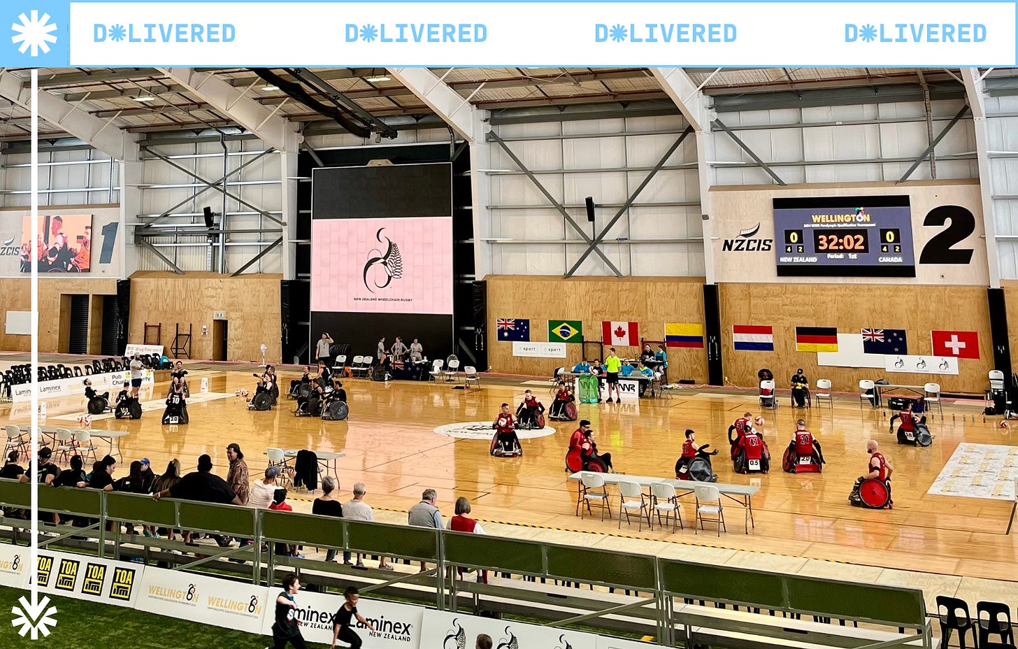 Image description: An indoor sports court with the New Zealand and Canada wheelchair rugby teams 