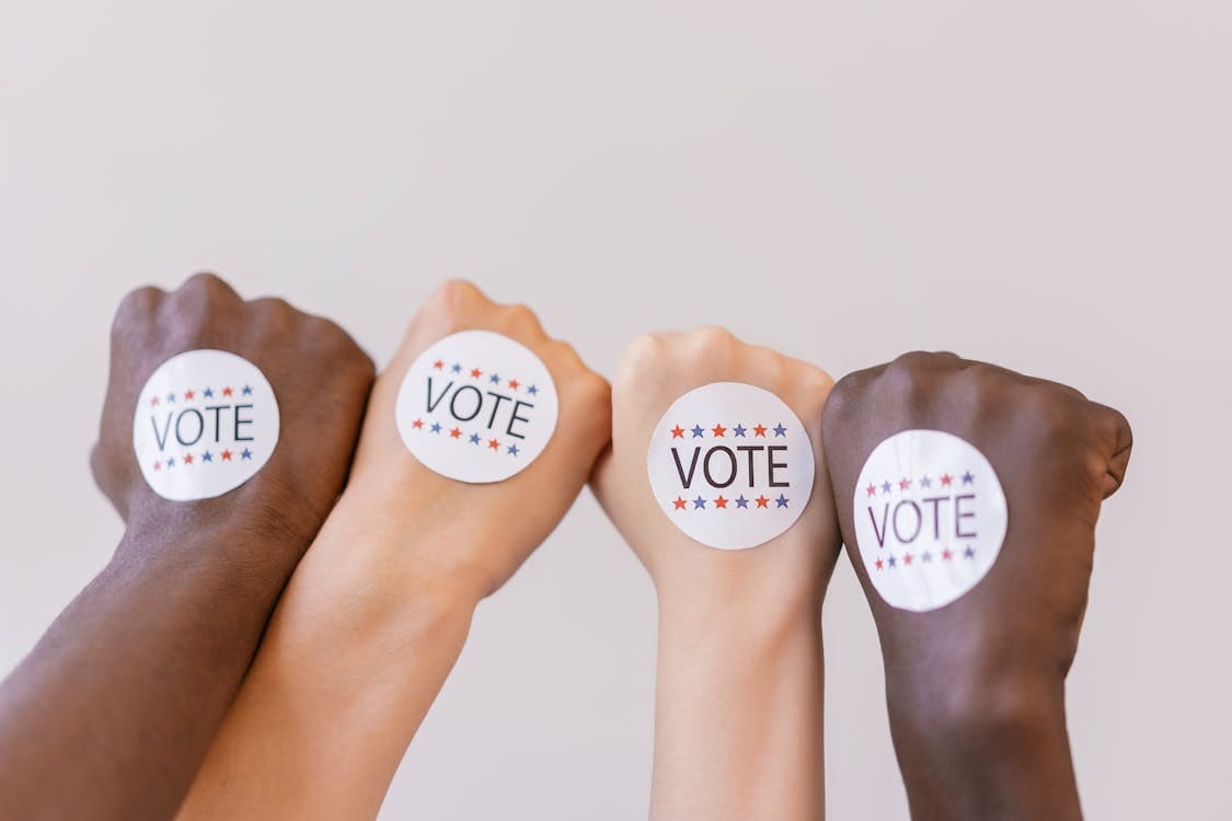 Free Close-up of diverse hands showing unity with vote stickers emphasizing democracy. Stock Photo