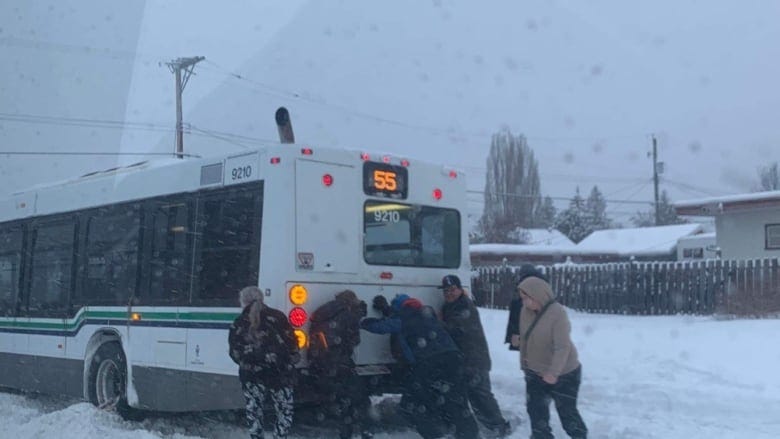 Passengers push a bus stuck in the snow in Prince George, B.C.