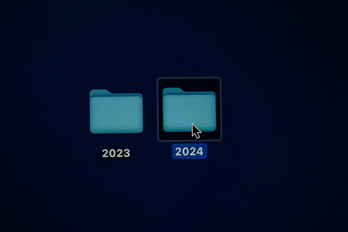 Two blue folders on a black computer screen, one labeled 2023, the other 2024. 
