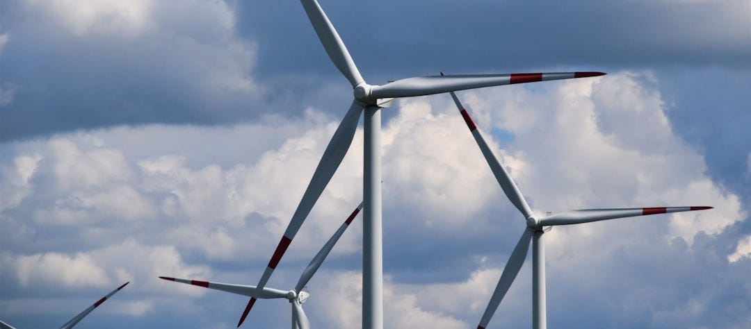 white and red wind turbine under blue sky during daytime