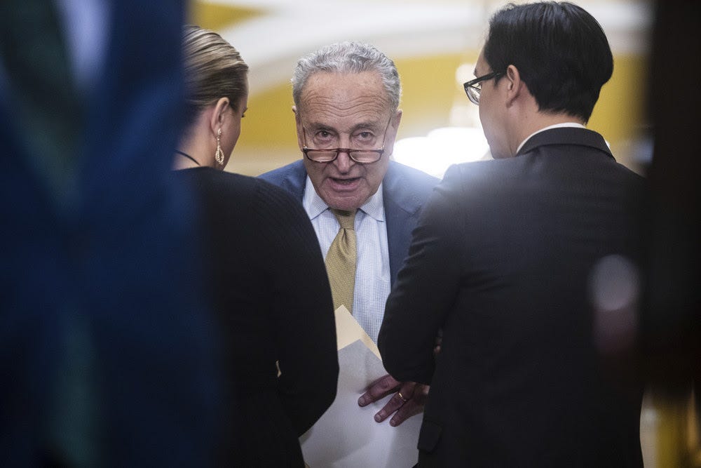Senate Majority Leader Chuck Schumer speaks with aides during a press conference at the U.S. Capitol.