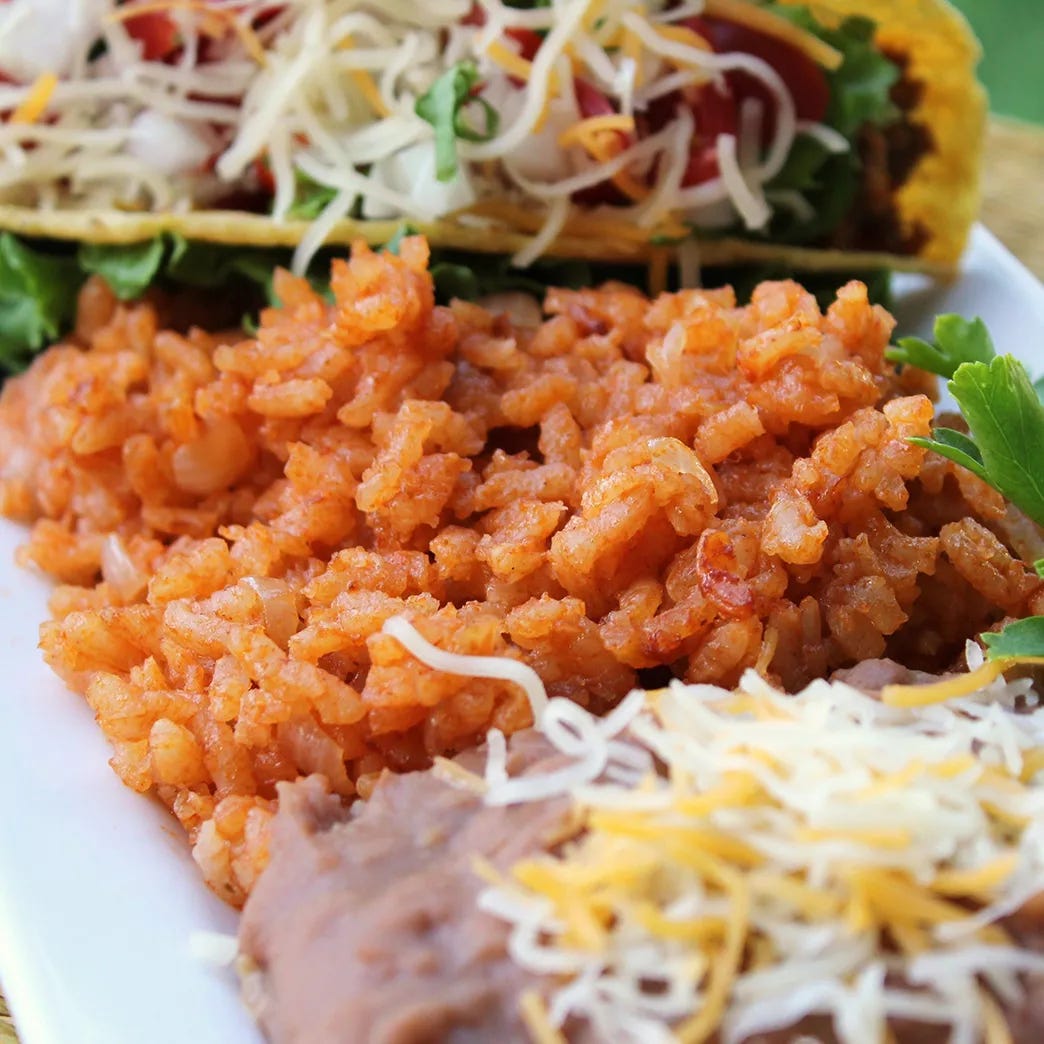 mid view of a plate of Mexican rice with tacos and refried beans
