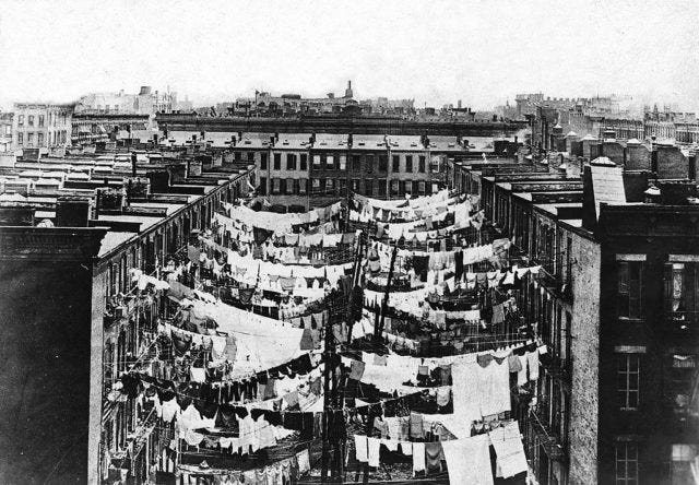 Two tenemant buildings viewed from a high angle, festooned with washing strung between them