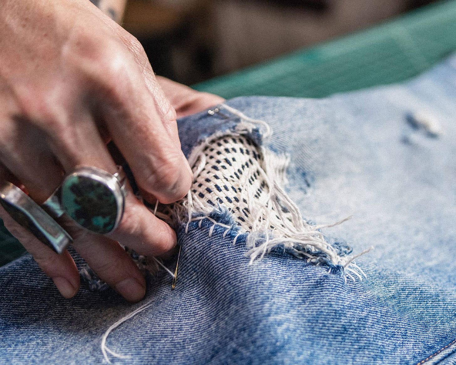 Person sewing together part of a jean.