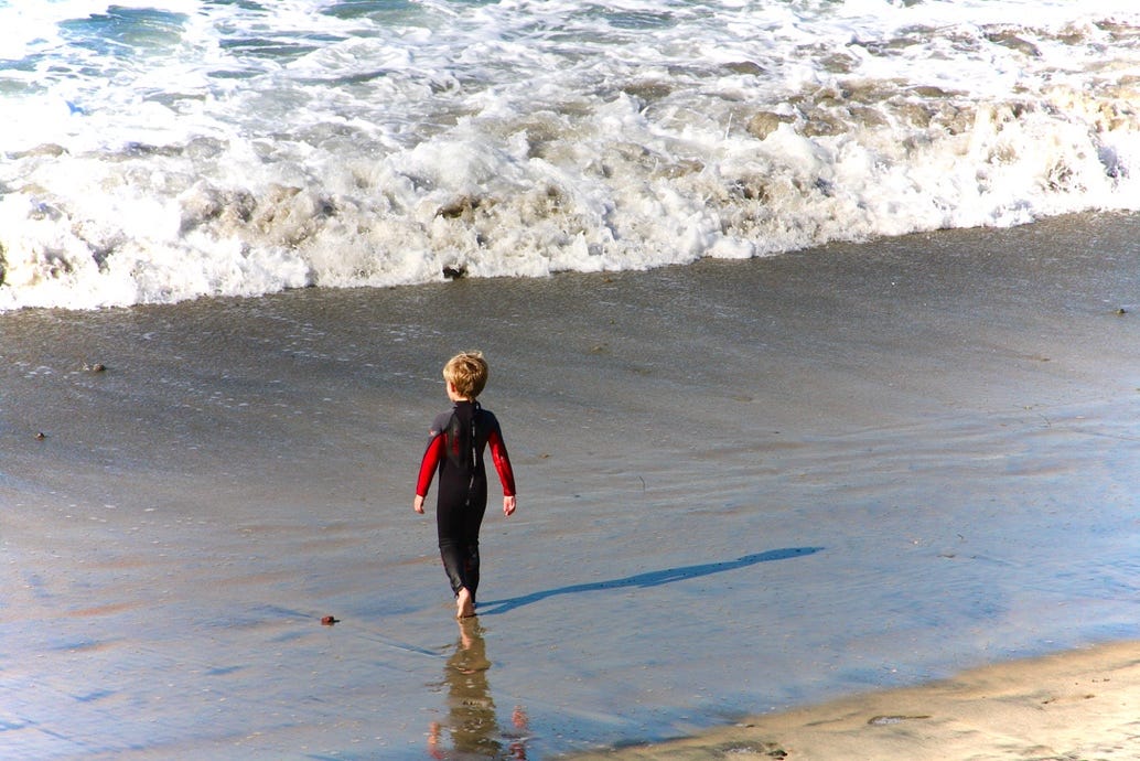 A child standing on the beach

Description automatically generated