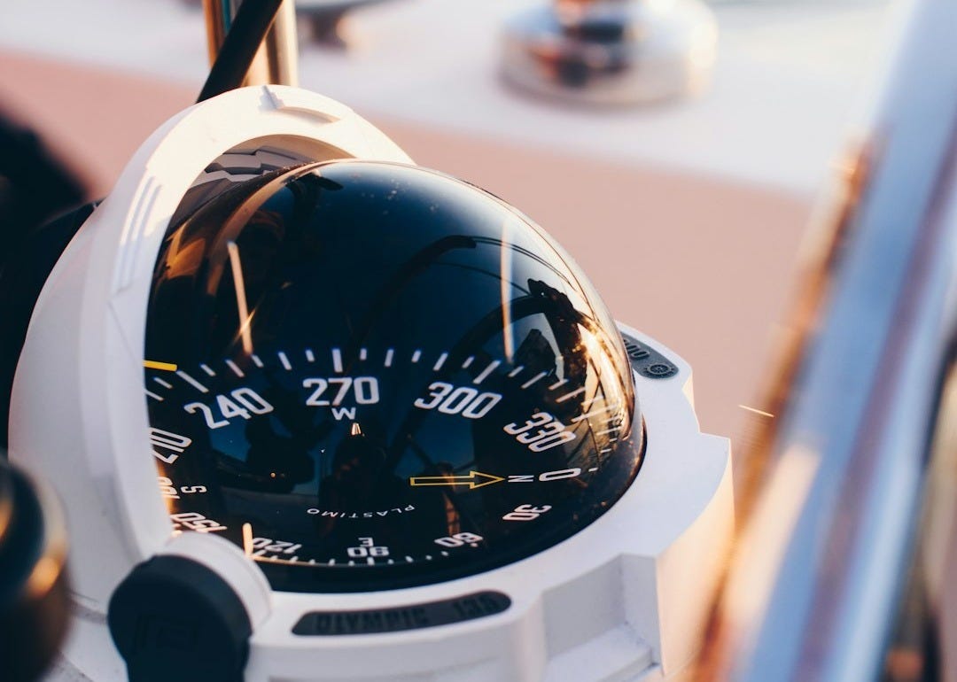 white and black compass pointing at 0 shallow focus photography
