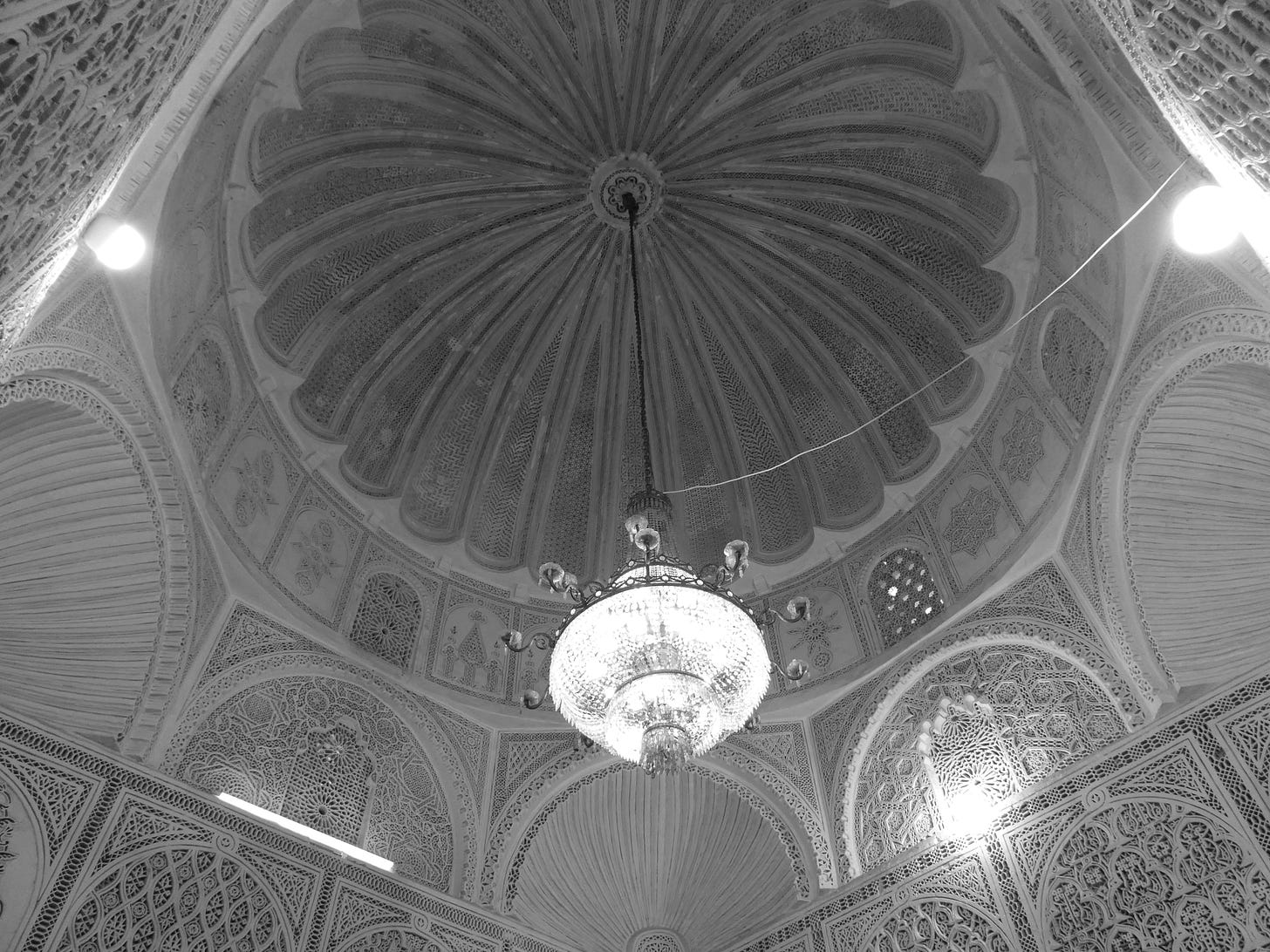 the stuccoed domed ceiling with a chandelier hanging in in the middle