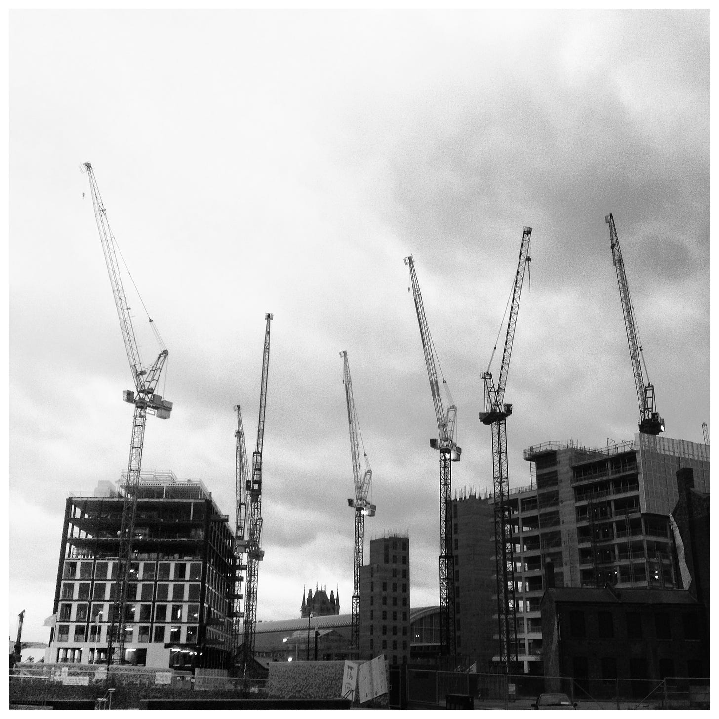 Black and white photo of construction cranes at Kings Cross in 2013. These buildings are all now finished.