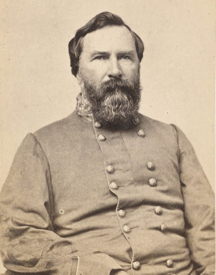 Black and white photograph of General James Longstreet. His is sitting in the pose wearing a service uniform. Serious look on his face. Full beard.