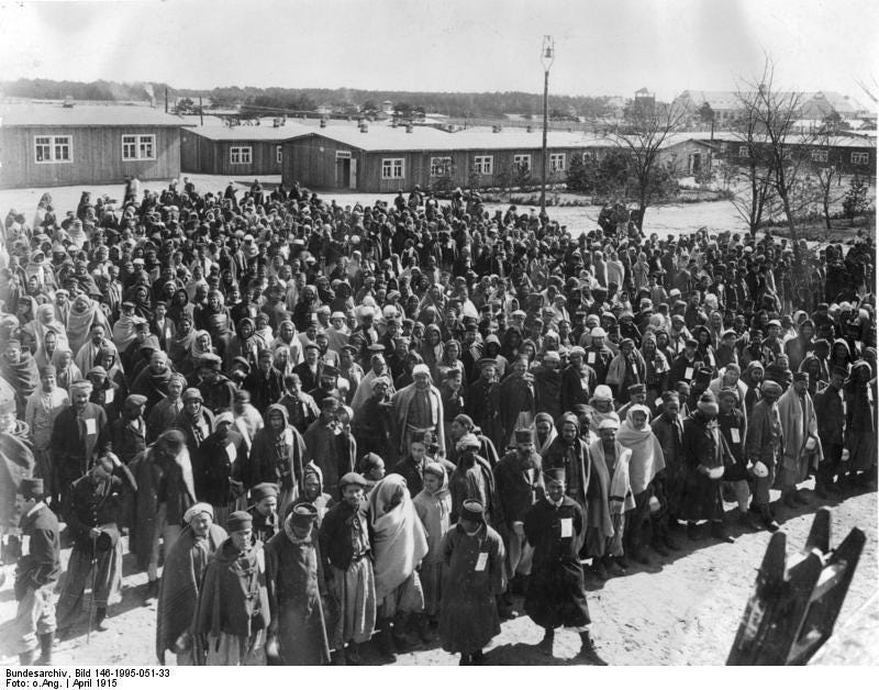 black and white photo showing a large number of people in middle eastern clothing in a prisoner of war camp