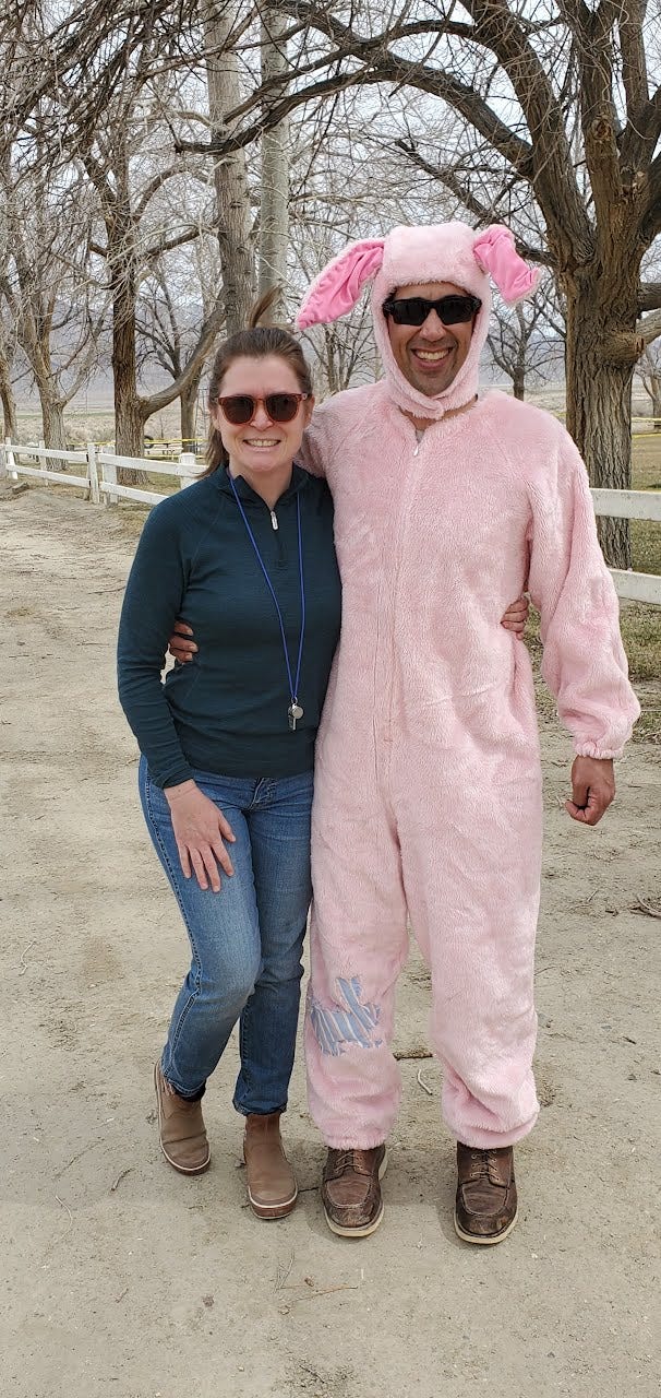Charlotte and Eric with arms wrapped around each other and smiling at the camera. Eric is wearing a pink bunny suit.