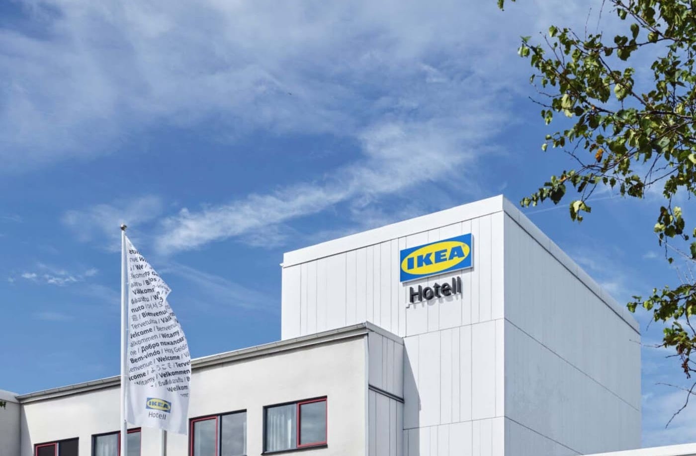 The white facade of the IKEA Hotell as it is today. Two people walk out of the hotel.