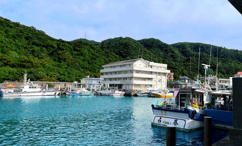 The calm blue water of the harbor in Green Island, Taiwan is ringed with lush green hills