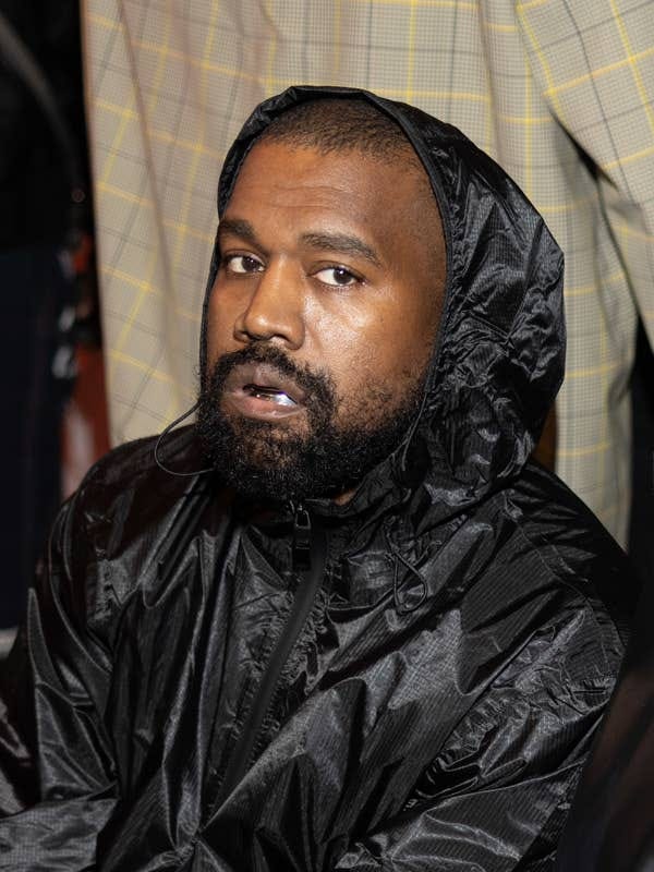 Kanye West in a hooded jacket looks towards the camera with a neutral expression