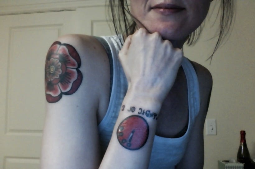 Selfie with my hand under my chin. My doomsday clock tattoo and rose tattoo on my left shoulder are uncovered. Both are bright red. 