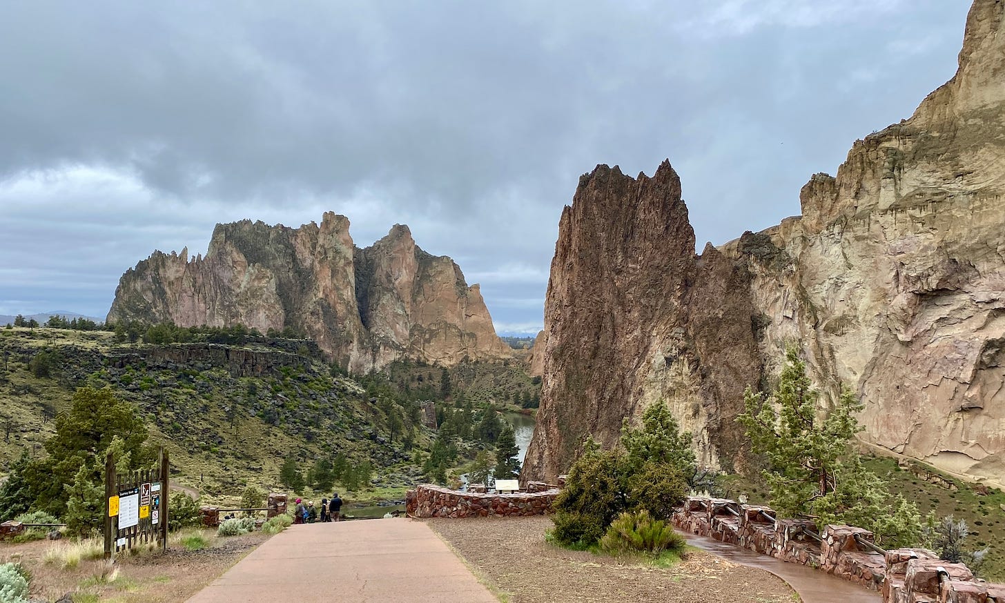 A photo of Smith Rock in Oregon. The sky is heavy with dramatic gray clouds and the steep cliffs of Smith Rock stand sharply against the sky.