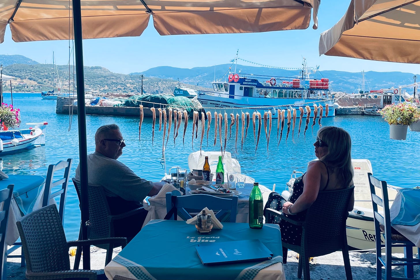 Two diners ignore the row of drying octopus legs in Molyvos