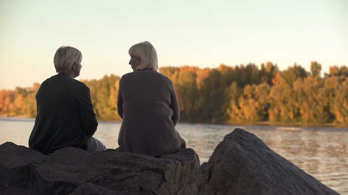 Friends consoling each other while overlooking a lake.