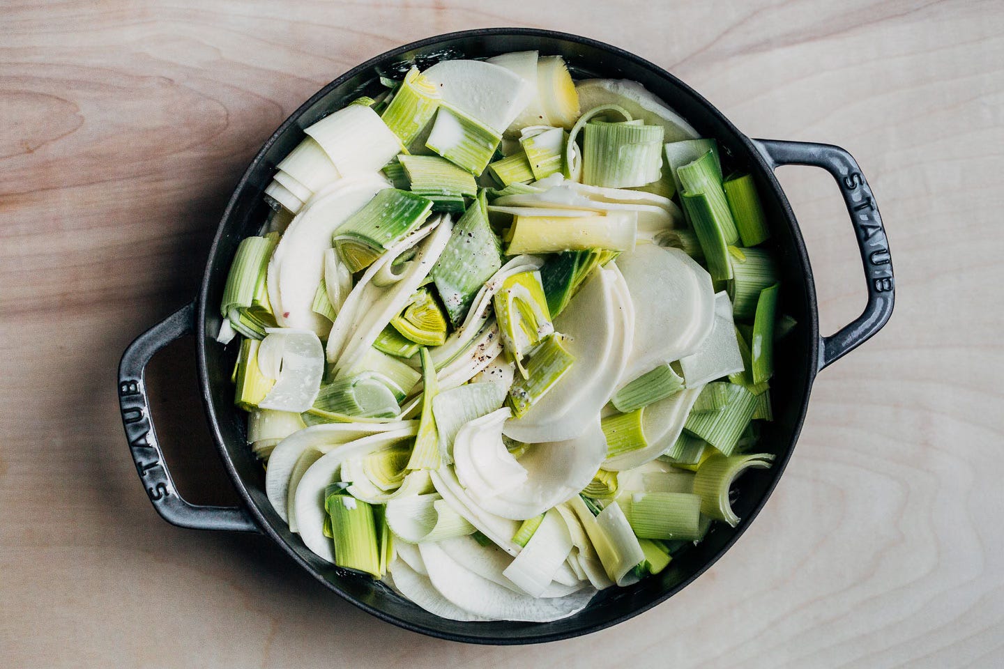 A baking dish with turnips, leeks, and cream, ready to bake. 