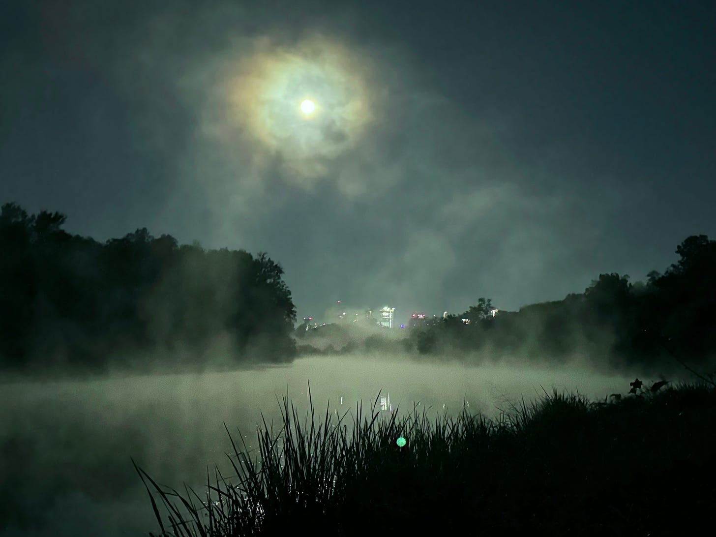 Moon over foggy river with skyline in background