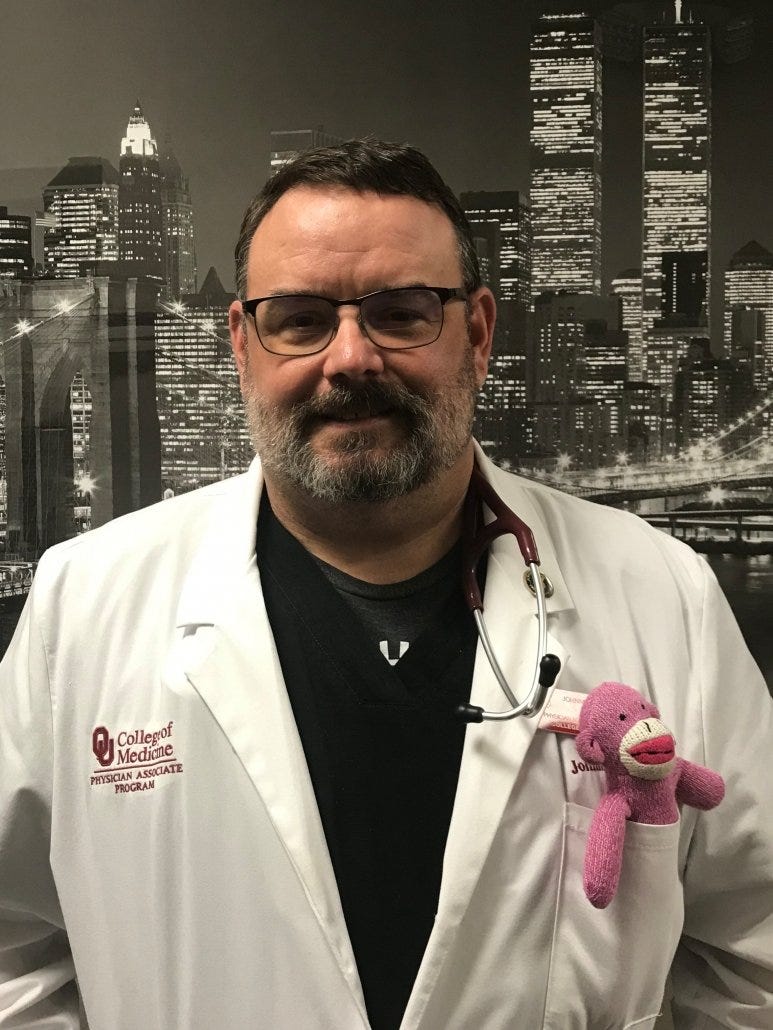 Johnnie Gilpen on a clinical rotation with "George," the pink sock monkey he uses to break the ice with patients, especially children.