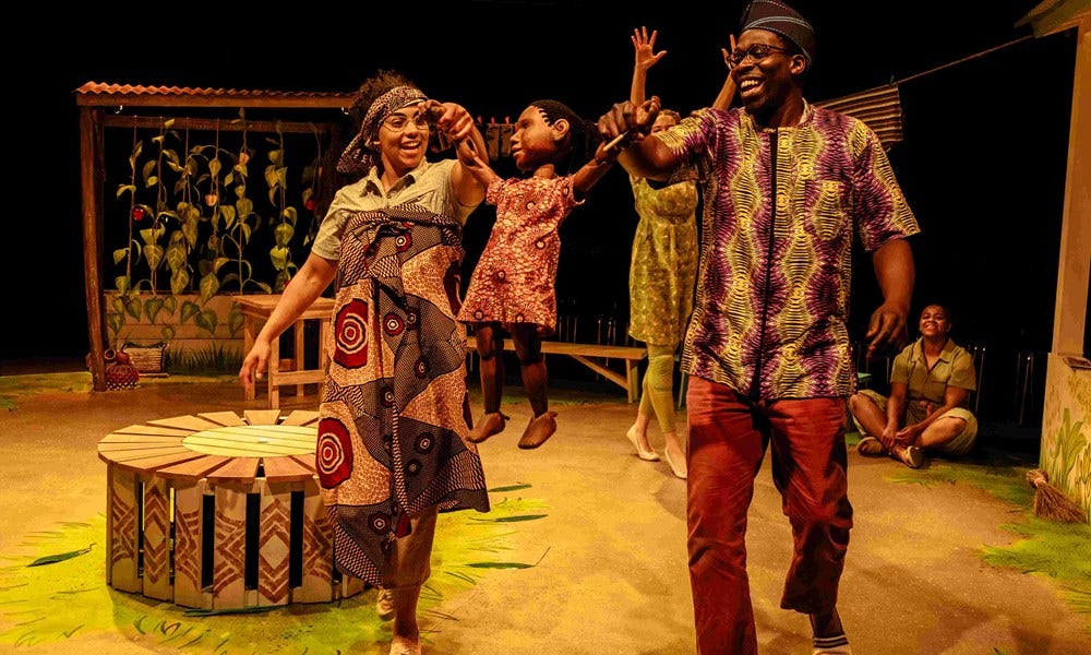 Woman and man dancing with little girl puppet wearing African traditional fabrics