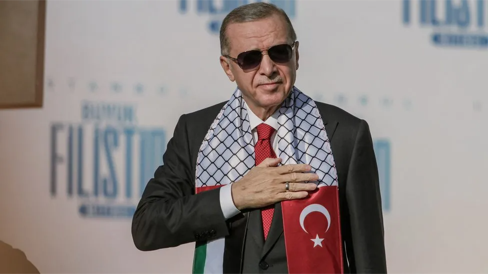 Turkish President Recep Tayyip Erdogan wears a scarf with the Turkish flag on one end and the Palestinian one on the other