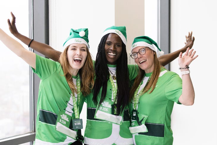 December 2024 in London: Three women wearing green Santa hats and t-shirts and cheering