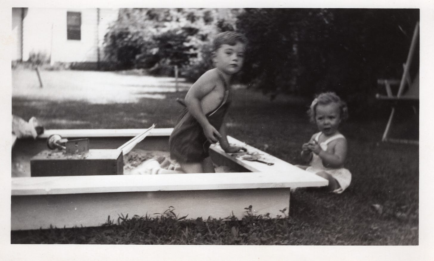 Black and white photo of two children playing in a sandbox