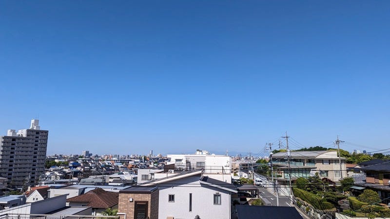 A view of a Nagoya neighborhood from a three-story roof deck, showing houses, apartment buildings, and the street