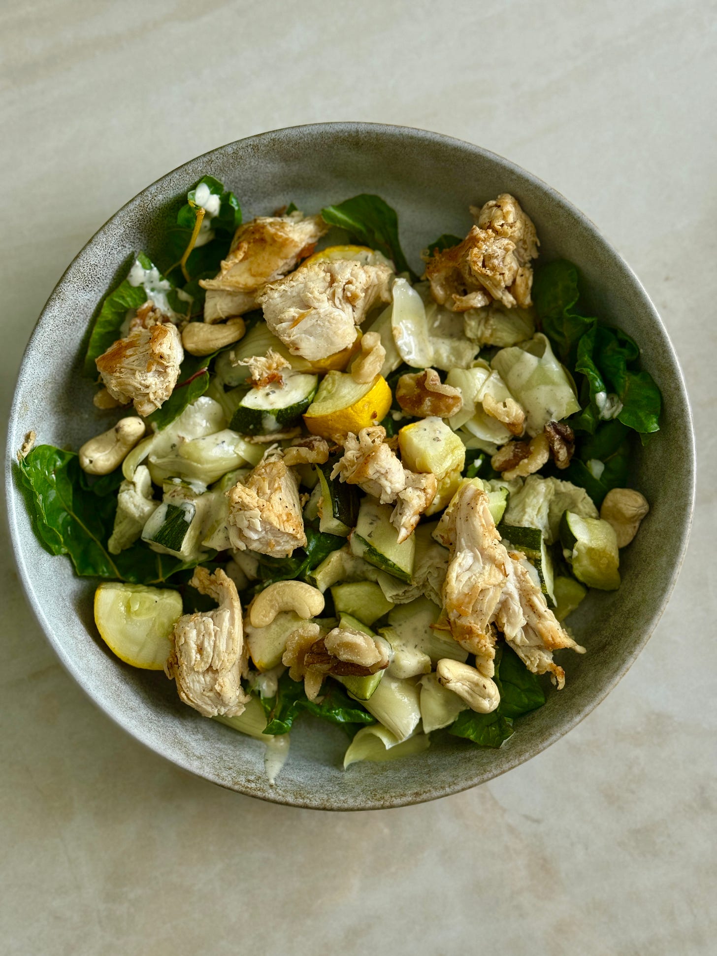 Pan-seared chicken with roasted zucchini and yellow squash, served over mixed greens with artichoke hearts, nuts, and drizzled with green goddess dressing.