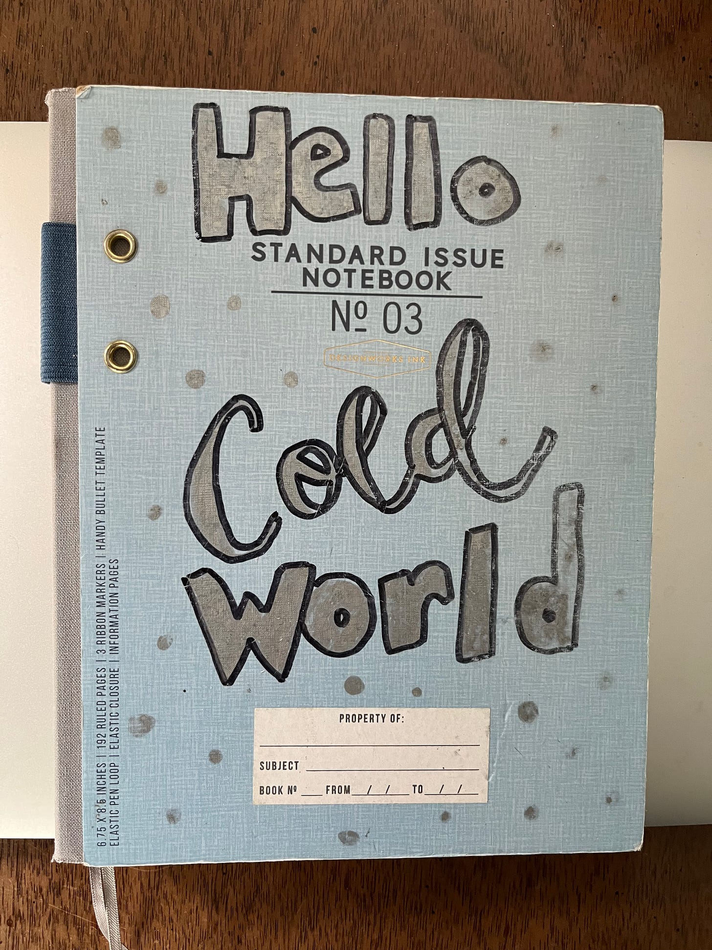 Picture of my Writing Notebook for With Love, from Cold World, that says "Hello Cold World" in silver sharpie on the cover with some little silver sharpie dots that are supposed to be like snowflakes
