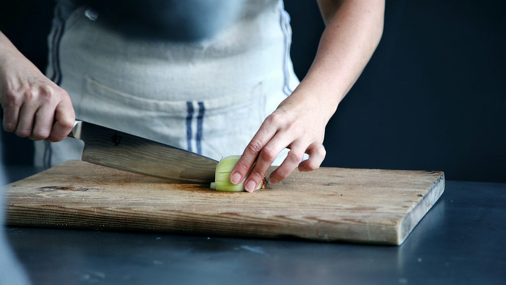 Chef cutting cucumber with knife.